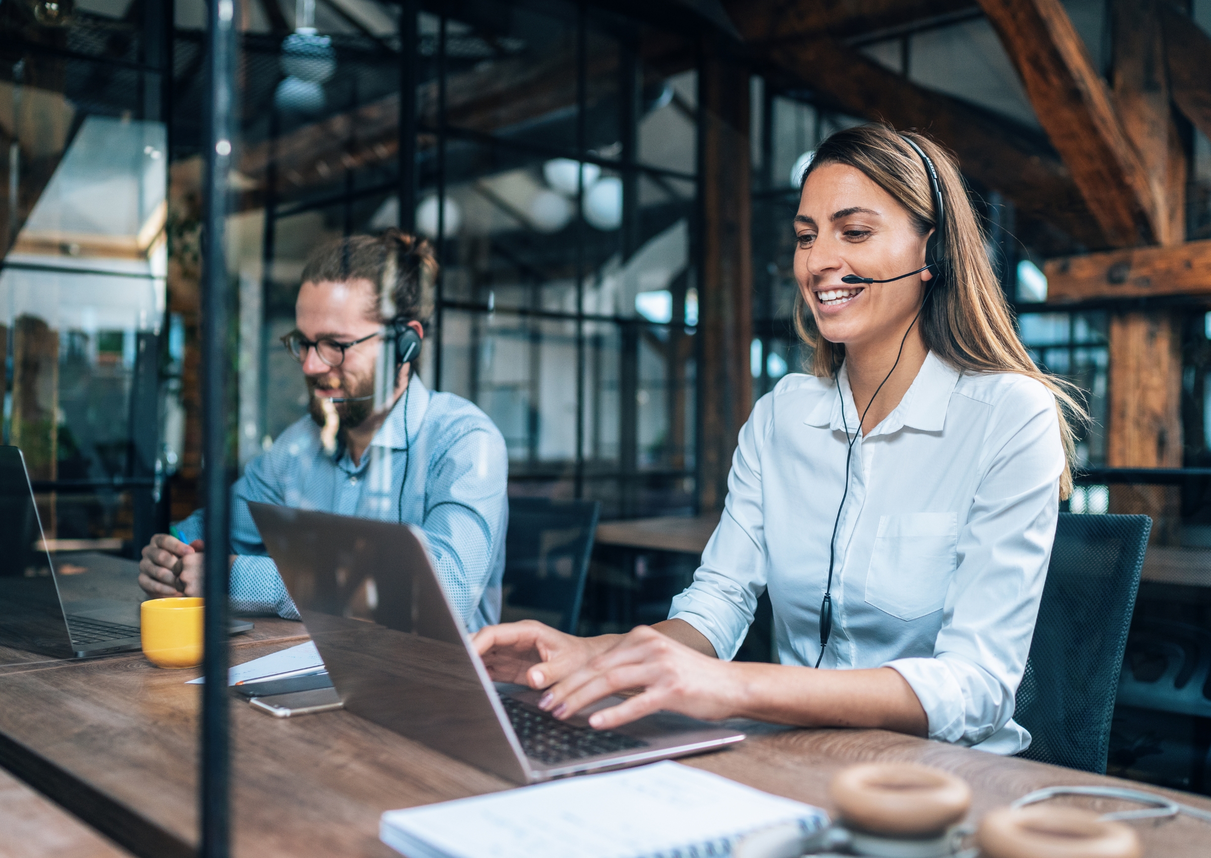 Mitarbeiterin und Mitarbeiter im digitalen Kundenservice der DSV, mit Headset am Laptop in modernem Büro